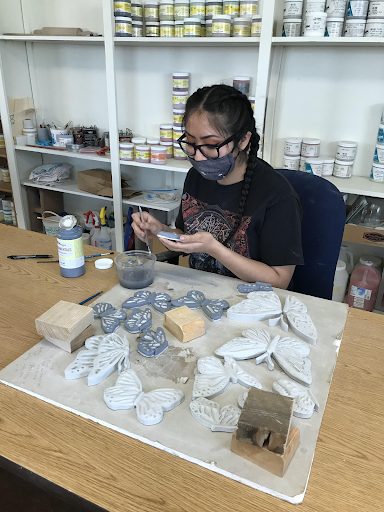 Apprentices glazing tile wearing a face mask